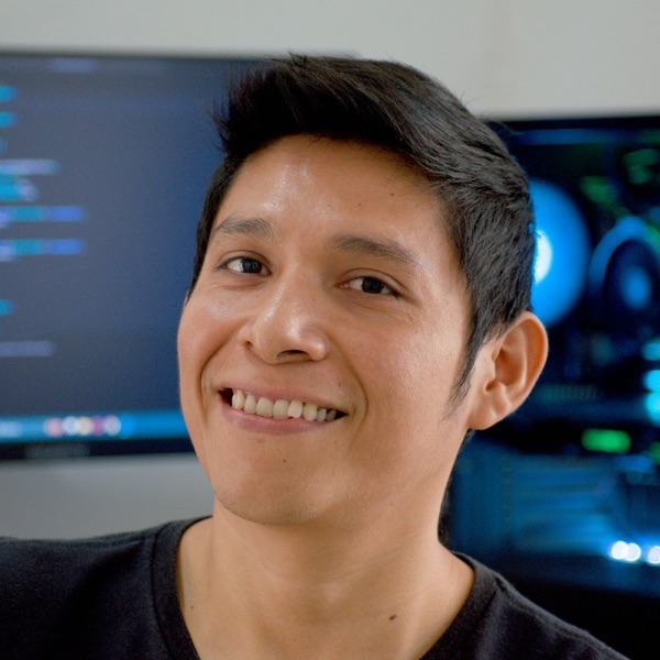 Roger Bacab sonriendo frente a un monitor con código